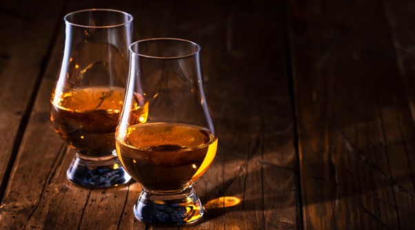 Two glasses of whisky on an oaken table